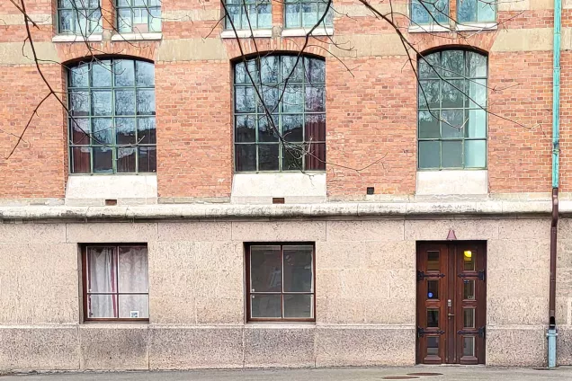 Red brick wall with slatted windows and door with eight panes. Photographer Christel Holmberg.