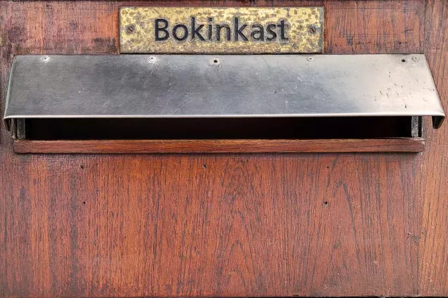 Brass sign with the word book drop in Swedish. Photographer Christel Holmberg.