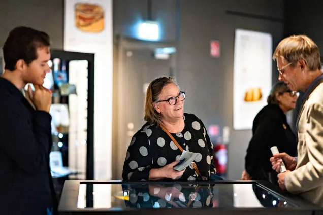 Besökare är samlade kring en glasmonter för att lyssna till en guide.